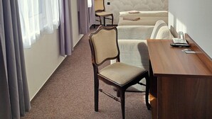 Hotellihuone, jossa on sänky, työpöytä, tuoli, televisio ja taulu seinällä.