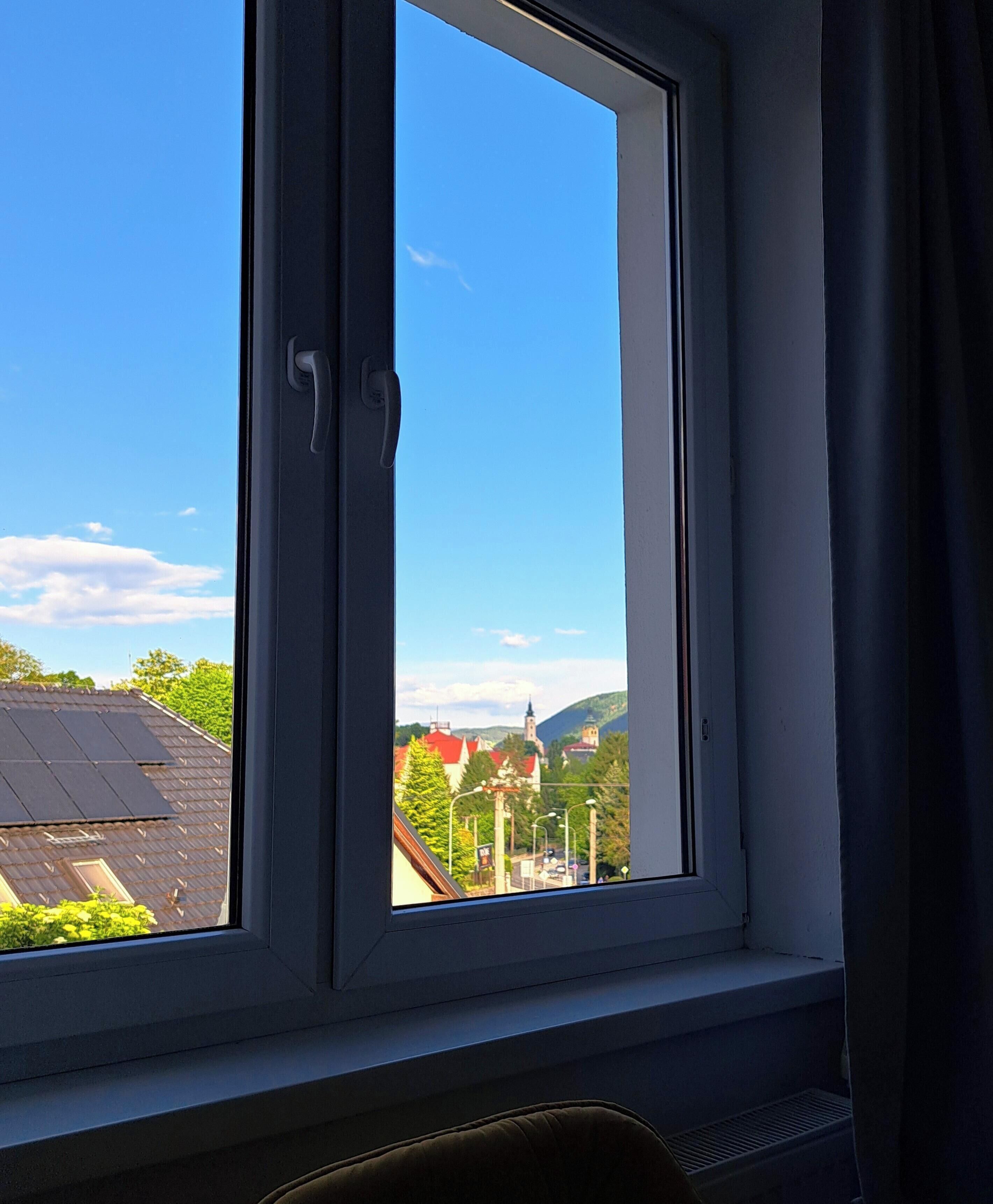 Une fenêtre donnant sur une ville, avec vue sur des bâtiments et une église.