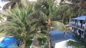 A residential area with a tall palm tree, a blue-roofed building, and a car parked nearby. - Baia Verde (Tarrafal)