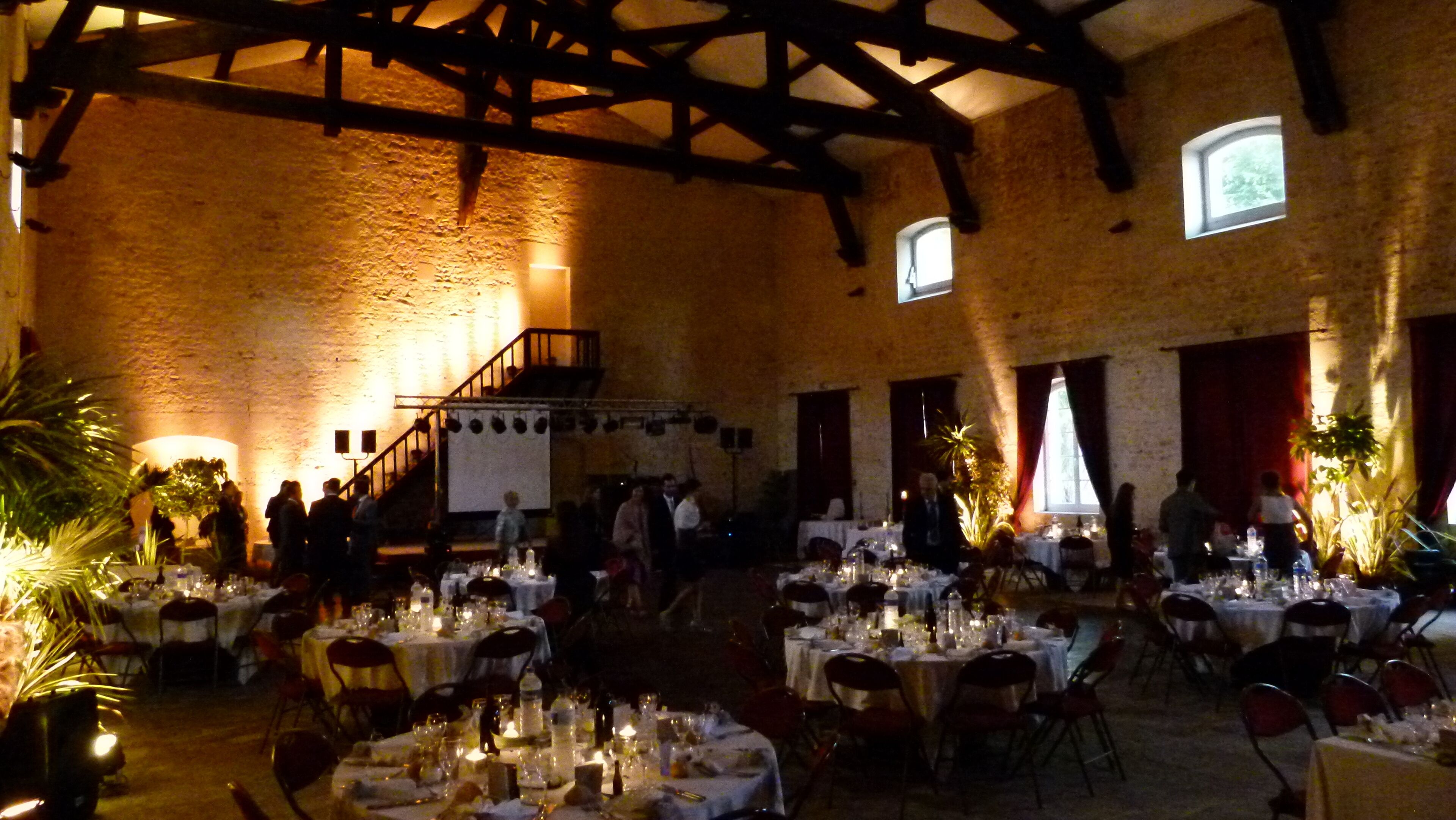 A banquet hall with high ceilings and exposed beams, tables set for a formal event, and natural light from windows.