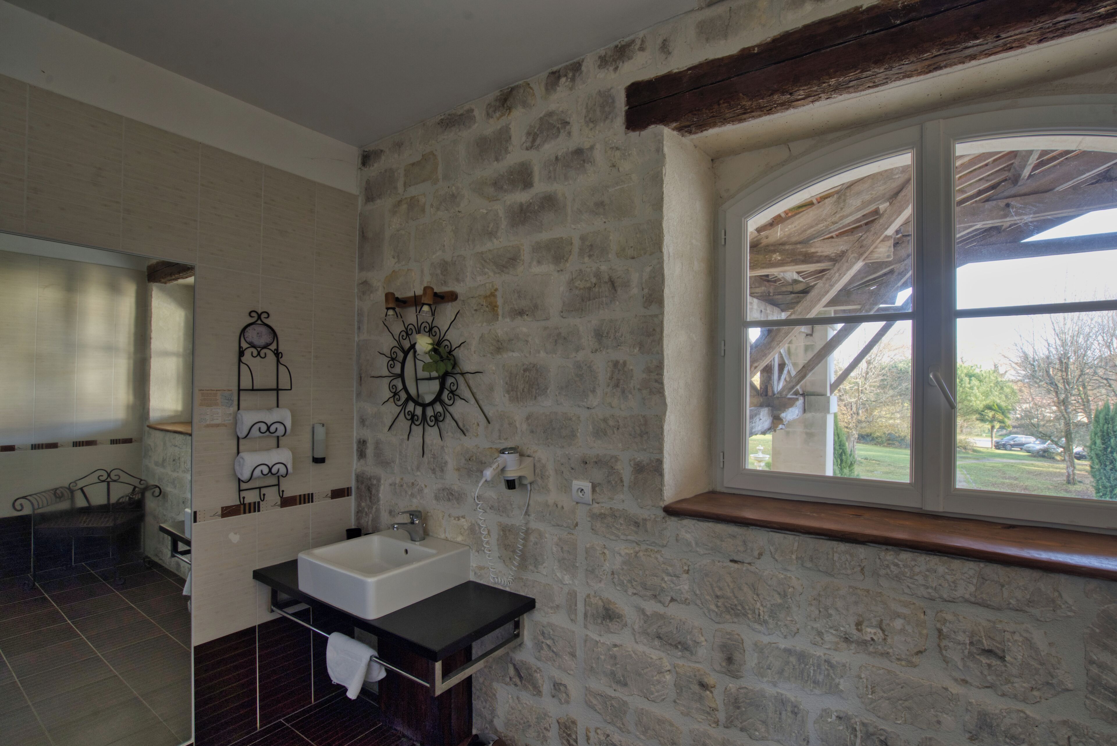 Ein Badezimmer mit Steinwand, Fenster, Waschbecken und Spiegel.