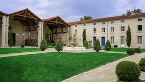 A building with a courtyard, a fountain, and neatly trimmed hedges. - Domaine des Chais (Thenac)