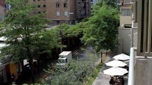 A courtyard with trees, a pathway, and buildings in the background. - Departamentos Centro Urbano Providencia (Santiago)
