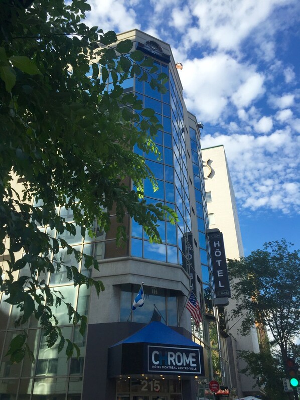 Un bâtiment d’hôtel doté d’une façade en verre, une enseigne indiquant « Hôtel » et une plus petite enseigne portant la mention « CHROME HOTEL MONTREAL CENTRE-VILLE ».