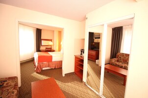 A hotel room with a bed, a desk, a sofa, and a mirror.