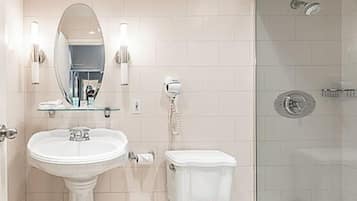 Une salle de bain comprenant un lavabo sur colonne, des toilettes, une douche à parois de verre et un miroir avec éclairage intégré.
