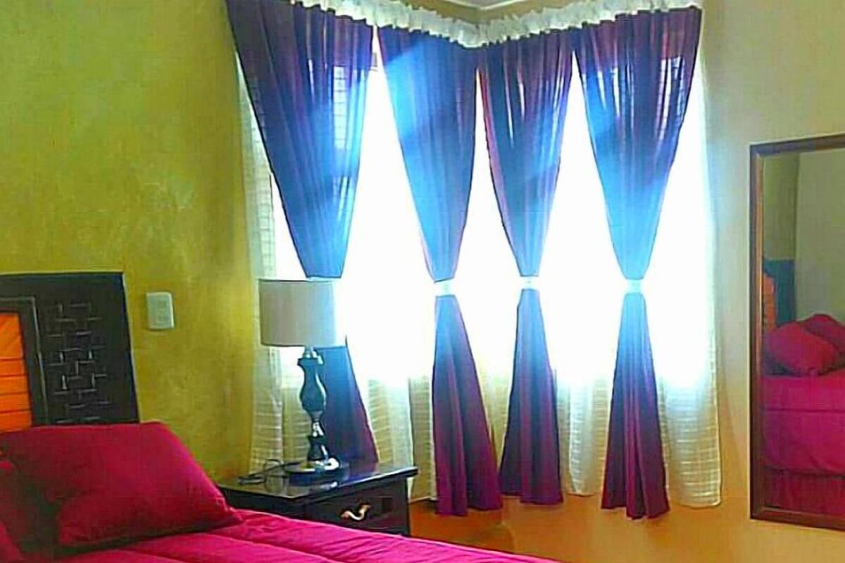 A bedroom with a large bed, a nightstand with a lamp, and a mirror on the wall.