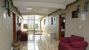A hallway with a patterned floor, a staircase, a red sofa, and a plant. - Hotel Milenio (Nanacamilpa)