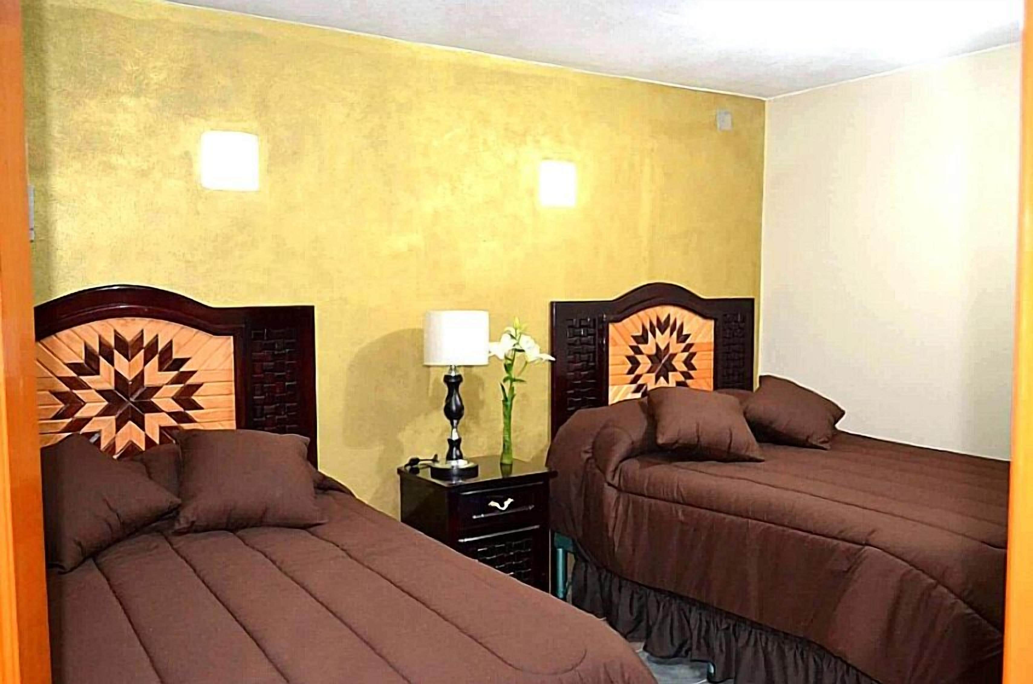 Een kamer met twee bedden, een nachtkastje en een muur met geometrische patronen.