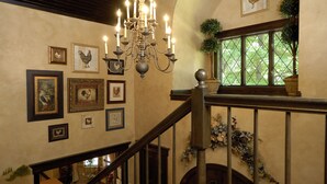 Un escalier orné d’un lustre, de tableaux encadrés et d’une cheminée.