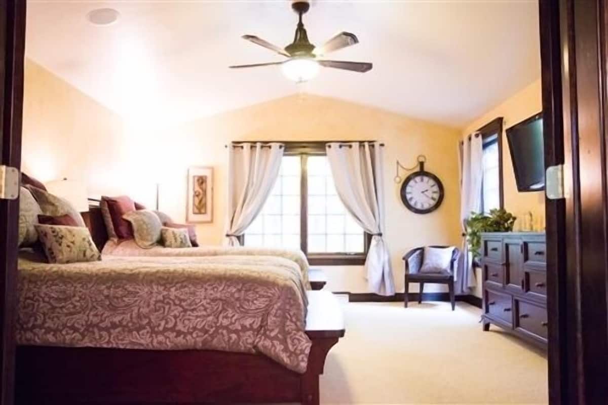 Un dormitorio con cama, cómoda, silla, reloj y ventilador de techo.