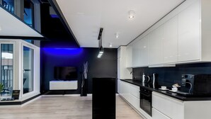 Een moderne keuken met witte kastjes, een zwarte aanrecht en een zwart keukenblok.