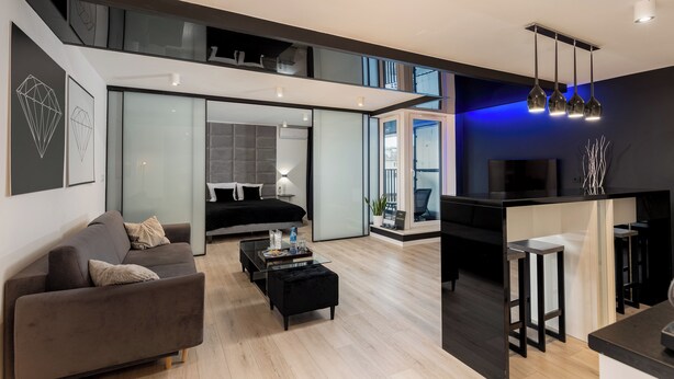 Een moderne woonkamer met een bank, salontafel en een televisie. Er is een trap die naar een verdieping leidt.