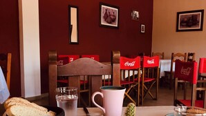 A dining area with tables set for meals, featuring bread, pastries, and beverages.