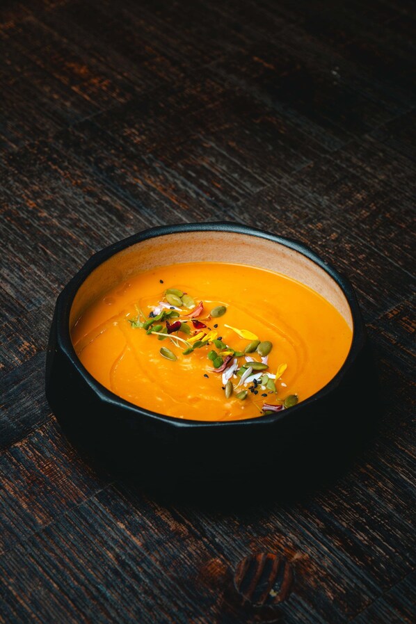 A bowl of soup with seeds and herbs on a wooden surface. - Hotel Tunqueley (San Martín de los Andes)
