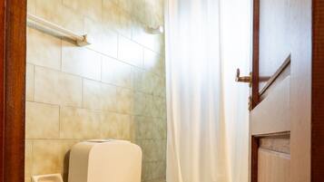 Un baño con dos inodoros, un bidé y una bañera con cortina.