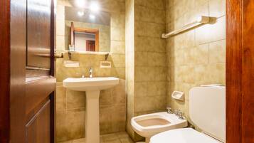 A bathroom with a sink, toilet, and bidet.
