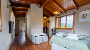Une chambre à coucher comprenant un lit, un bureau, une chaise, une télévision et une fenêtre donnant sur la montagne.