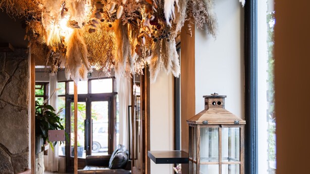 Un intérieur chaleureux avec un plafond en bois, une lanterne et un coin salon près d’une fenêtre.