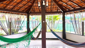 A room with a tiled floor, a wooden ceiling, and a view of palm trees outside. - Hotel Gran Minas (Vespasiano)