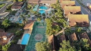 An aerial view of a residential area with multiple houses, a swimming pool, and a basketball court. - Hotel Gran Minas (Vespasiano)