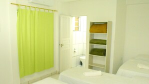 Una habitación con dos camas, baño y un armario con estantes.