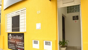 Un edificio amarillo con un letrero que indica Hotel Lize, que ofrece servicios como TV, internet, Wi-Fi y aire acondicionado.