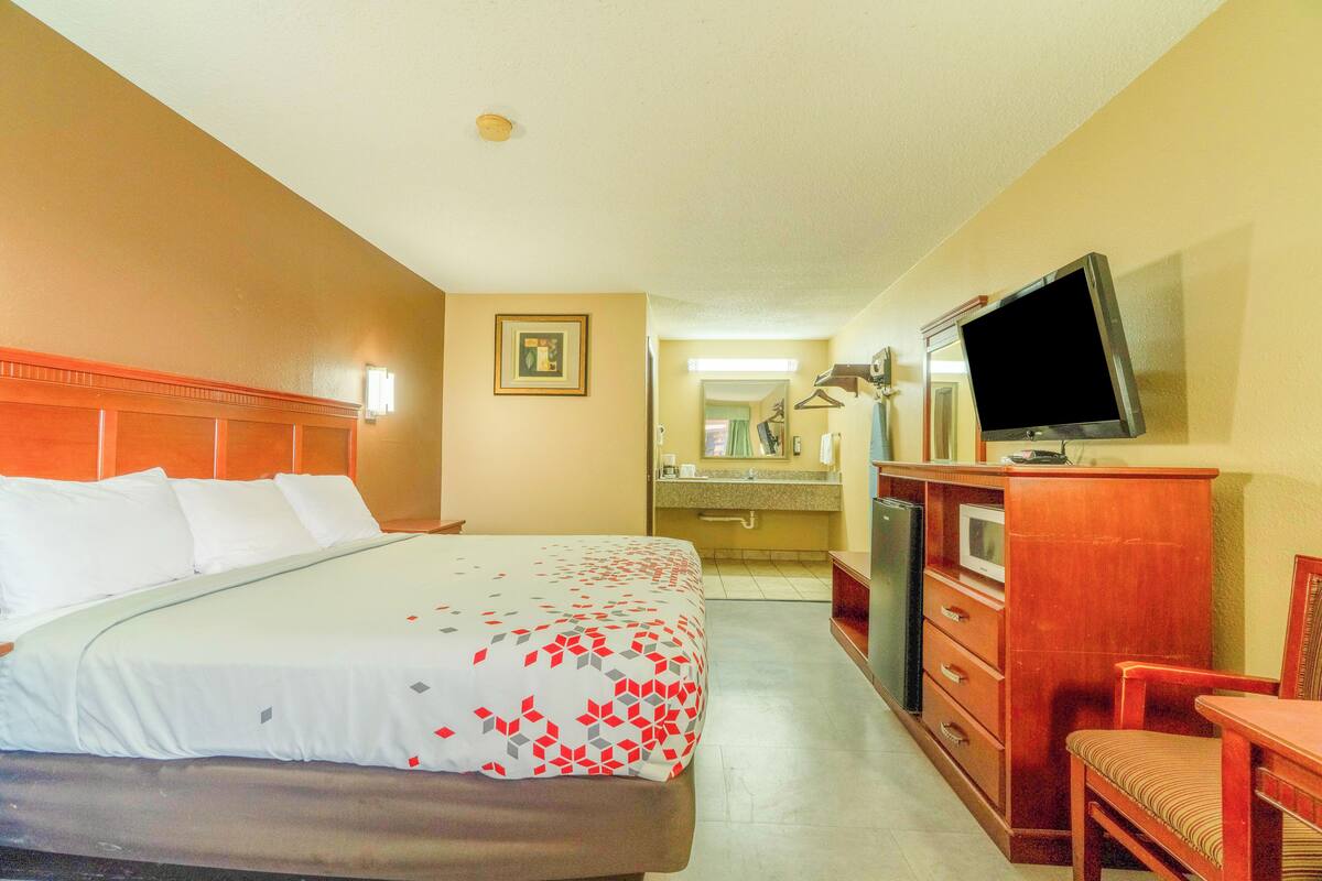 A hotel room with a bed, a television, a desk, and a mirror.
