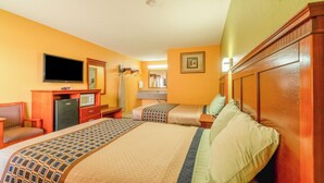 A hotel room with a large bed, a desk with a computer, a television, and a bathroom visible in the background. - Crown Inn (Denver City)