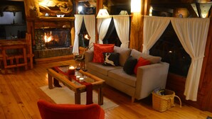 A cozy living room with a fireplace, wooden furniture, and a comfortable seating area. - Casa del Lago Villa La Angostura (Villa La Angostura)