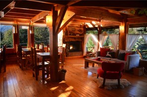 A cozy cabin interior with a wooden floor, a fireplace, a sofa, and a dining area. - Casa del Lago Villa La Angostura (Villa La Angostura)