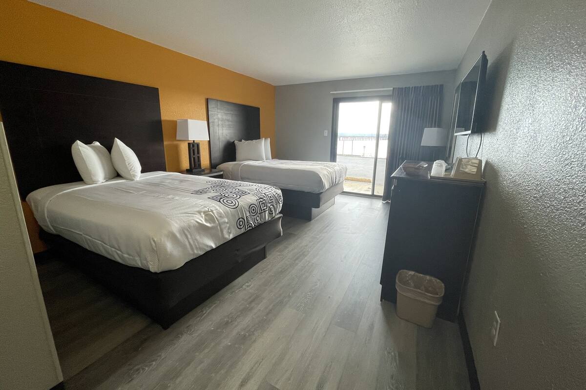 Ett hotellrum med två sängar, ett skrivbord, en tv och utsikt över stranden.