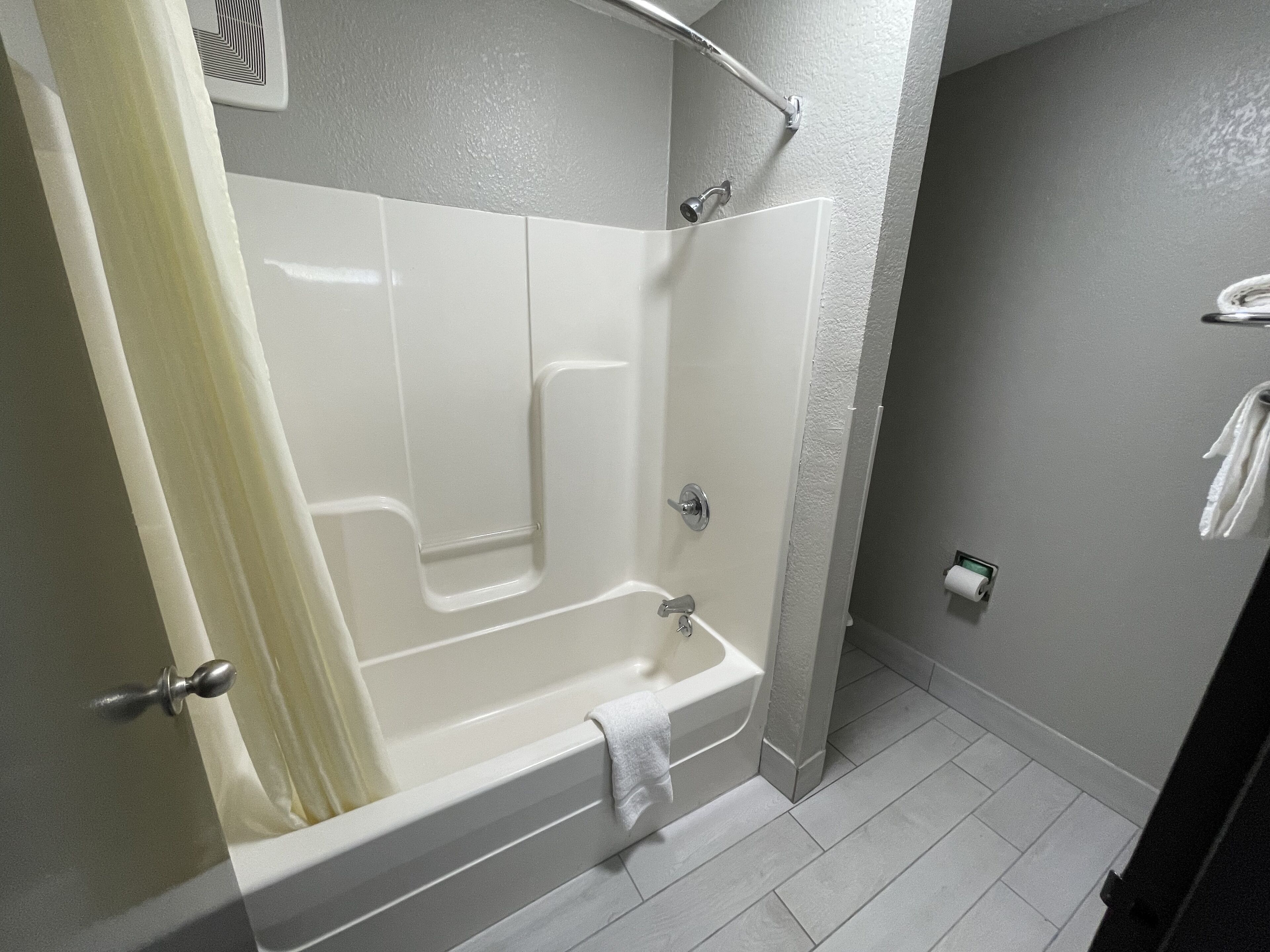 A modern bathroom with a bathtub, shower, and toilet.