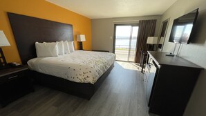 Hotelkamer met een bed, bureau, kledingkast en een groot raam met uitzicht.
