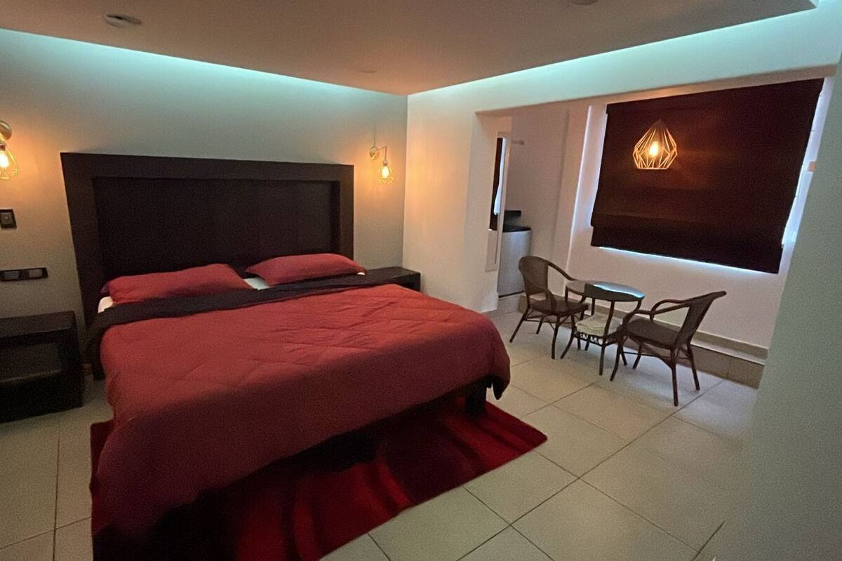 A bedroom with two beds, a desk, and chairs.