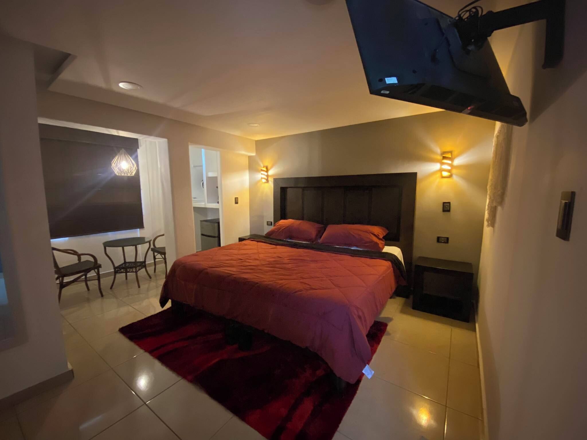 Ein Schlafzimmer mit Bett, Wand-Fernseher, Schreibtisch und Stuhl.