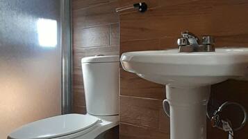 Un baño con inodoro, lavabo y cubo de basura.
