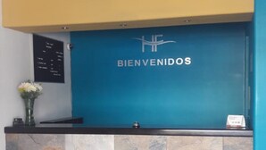 A reception desk with a blue backdrop and the word "BIENVENIDOS" in white letters. - Hotel Flores (Guamuchil)