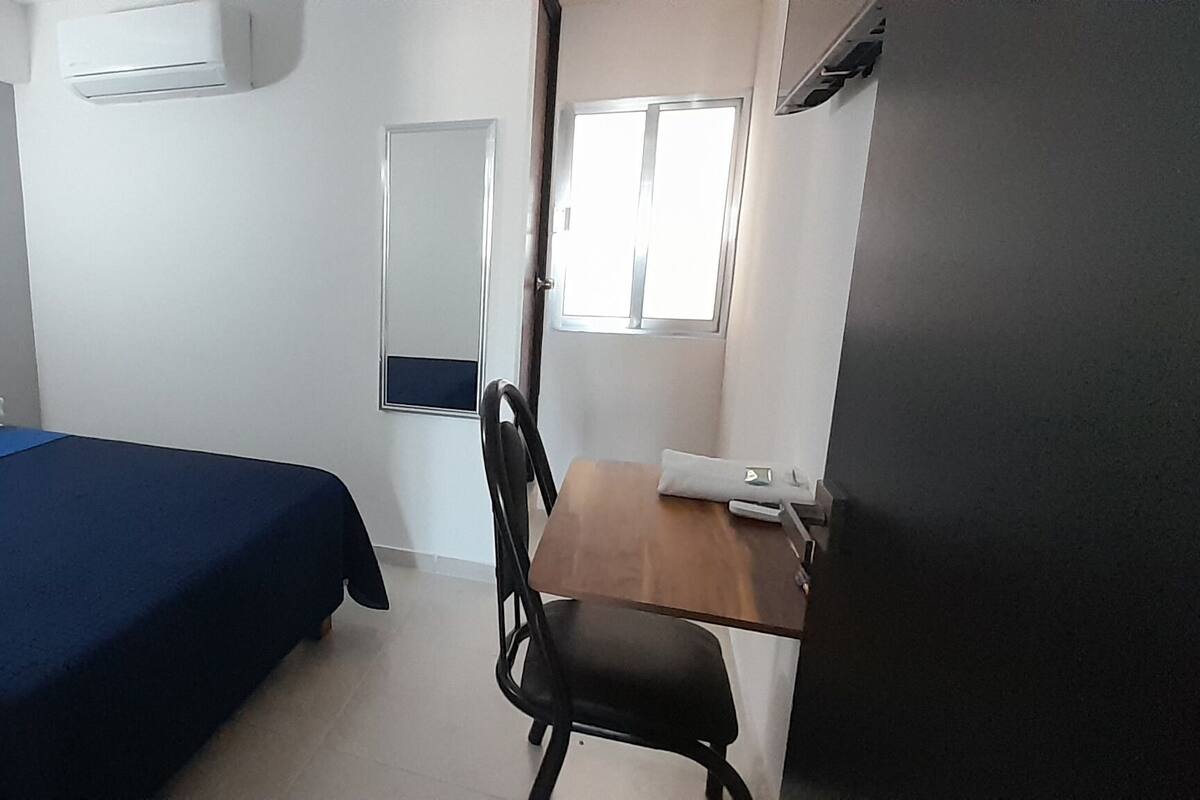 A bedroom with a bed, a desk, and a chair.