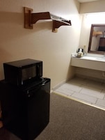 Habitación pequeña con microondas, un lavamanos y un espejo.