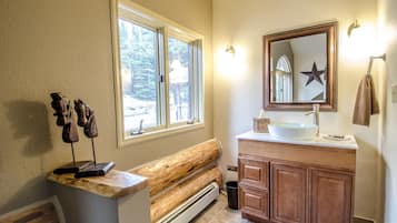 A bathroom with a wooden bench, a large mirror, and a sink with a star decoration.