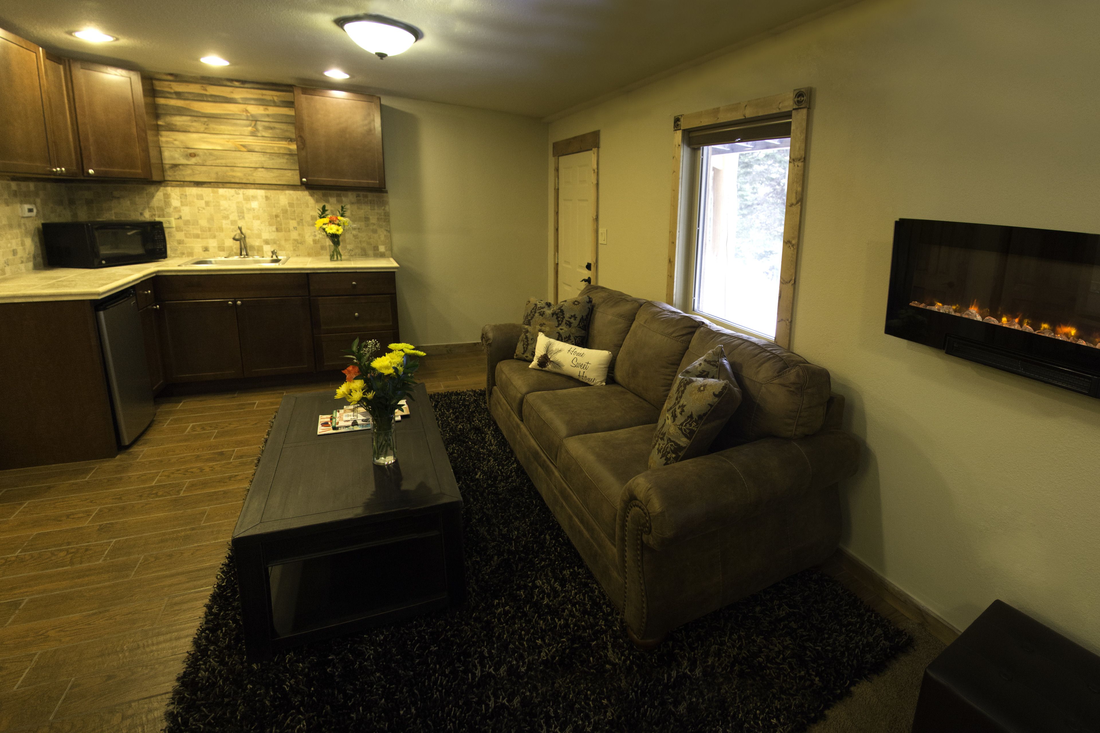 A modern living room with a brown couch, a coffee table, and a fireplace.