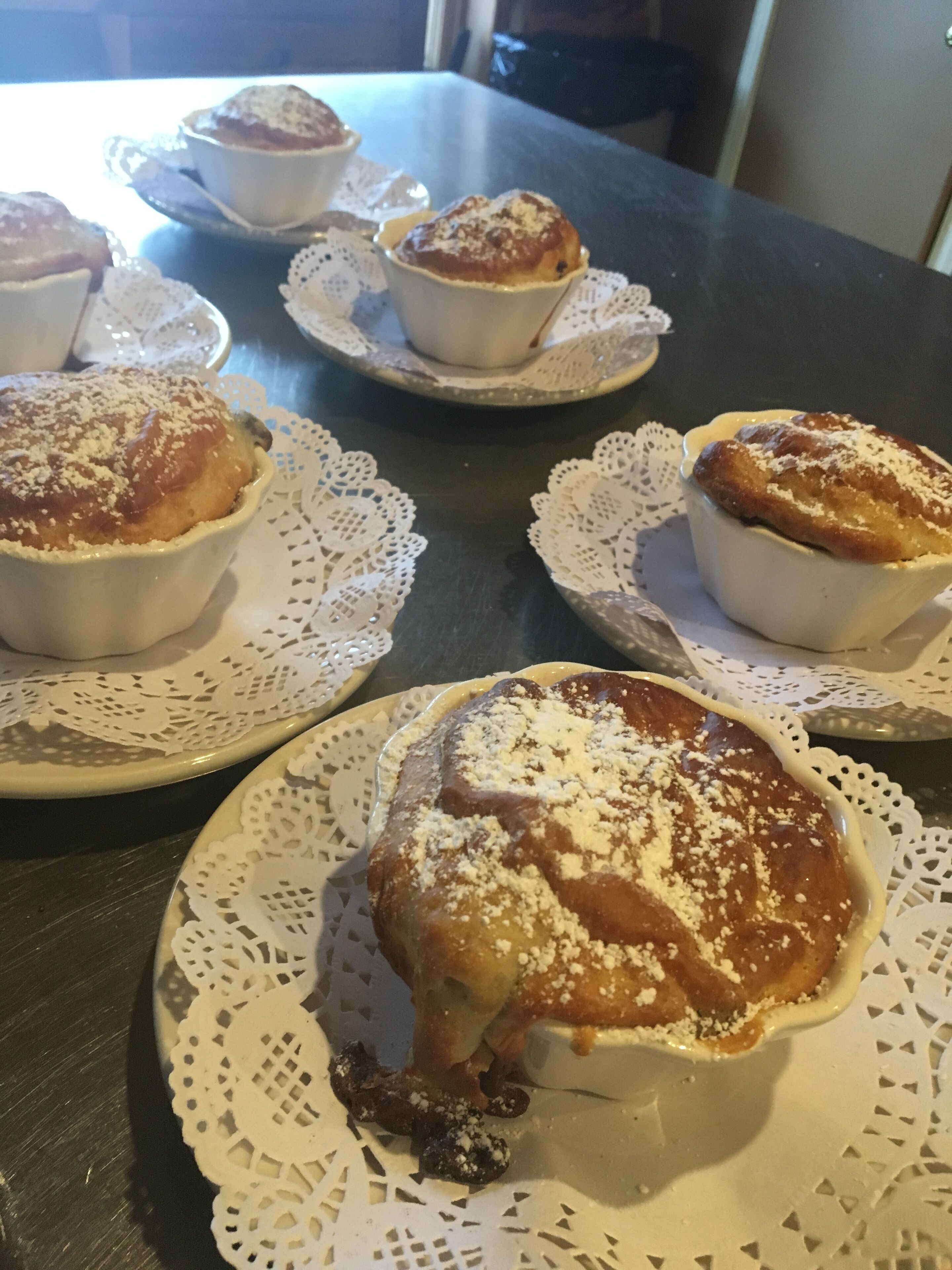 A table with several dishes of food, including what appears to be a type of bread or pastry, served on white plates with lace doilies.