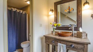 A bathroom with a wooden vanity, a large mirror, a chandelier, and a shower curtain.