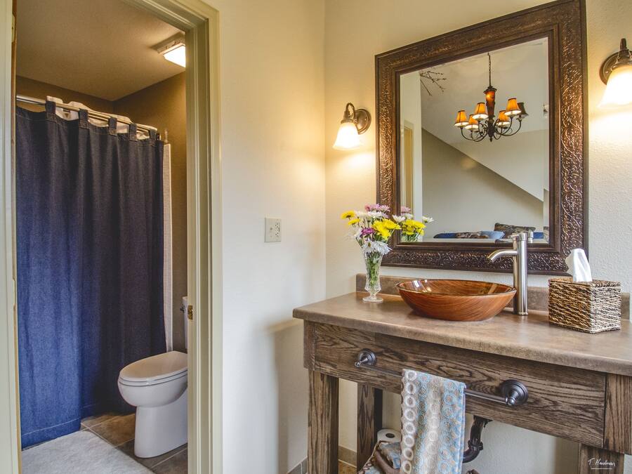 A bathroom with a wooden vanity, a large mirror, a chandelier, and a shower curtain.