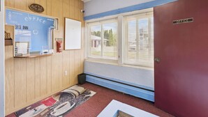 A room with a wooden paneled wall, a bulletin board, a window with blinds, and a door labeled "OFFICE". - Heidelberg Motel by Capital O Bridgeport Frankenmuth I 75 (Bridgeport)