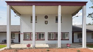 A building with a covered porch, white exterior, and red trim. - Heidelberg Motel by Capital O Bridgeport Frankenmuth I 75 (Bridgeport)
