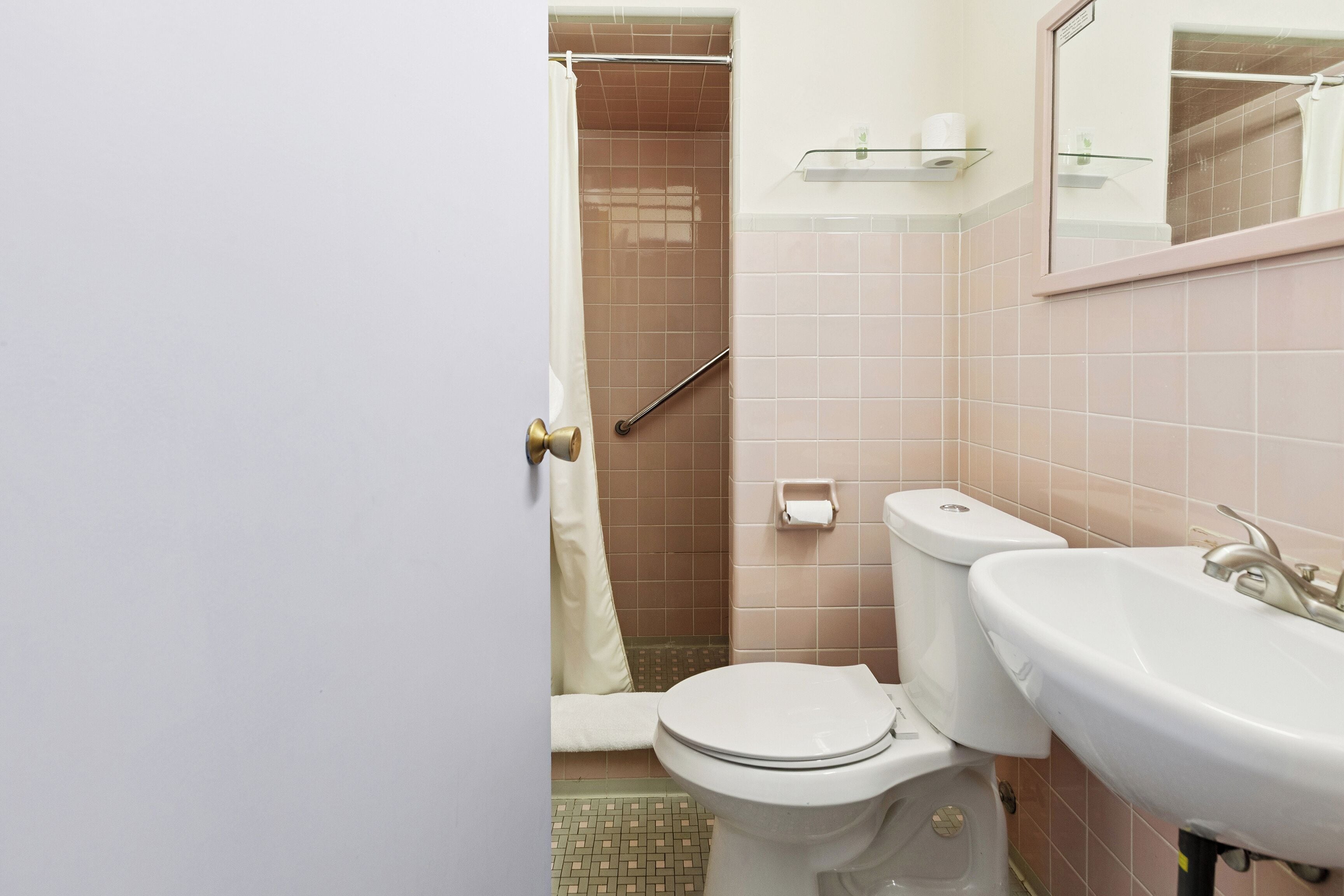 A bathroom with a toilet, sink, and shower area.