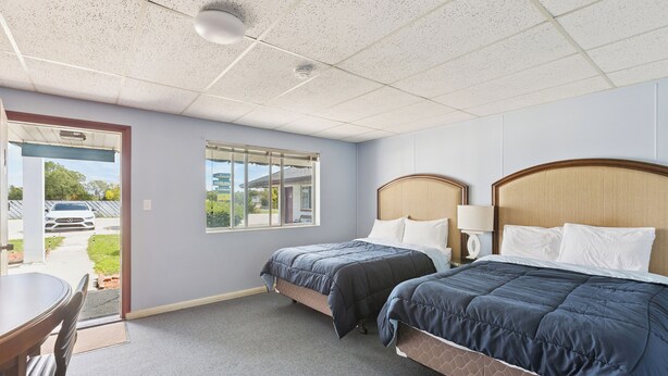A hotel room with two beds, a desk, and a window with a view of the outside. - Heidelberg Motel by Capital O Bridgeport Frankenmuth I 75 (Bridgeport)