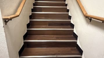 A wooden staircase with a handrail on both sides, leading to a landing with four framed pictures.